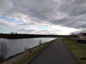 Empty road by river against sky