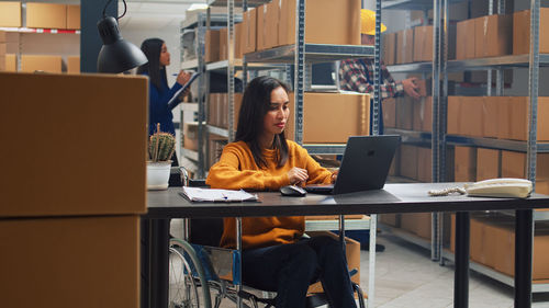 Young woman using laptop while sitting on table