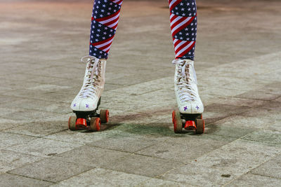 Low section of woman wearing american flag leggings while roller skating on footpath