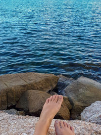 Low section of woman on rock by sea