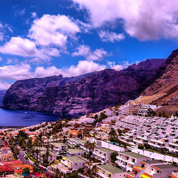 mountain, building exterior, architecture, sky, built structure, mountain range, residential district, cityscape, town, city, cloud - sky, high angle view, residential structure, townscape, crowded, residential building, house, cloud, water, scenics