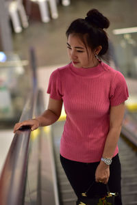 Young woman looking away while standing on escalator