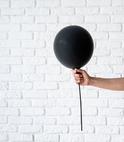 Man holding balloons against white wall