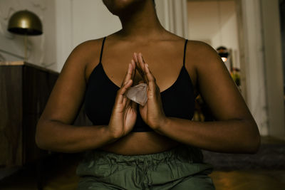 Midsection of woman holding crystal while exercising at home