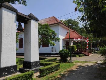 Houses by trees and buildings against sky