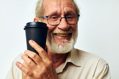 Smiling man showing coffee cup against white background