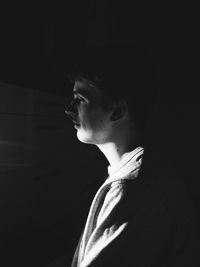 Portrait of young man looking away against black background