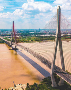 Suspension bridge over river against cloudy sky