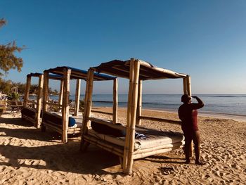 Rear view of woman standing by bed at beach