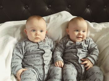Cute baby boys sitting on sofa at home