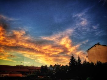 High section of silhouette houses against dramatic sky