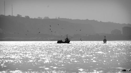Silhouette people on sea against clear sky