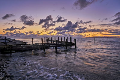 Pier over sea against sky during sunset