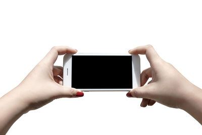 Cropped hands of woman using smart phone against white background