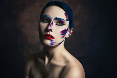 Portrait of young woman wearing mask against black background