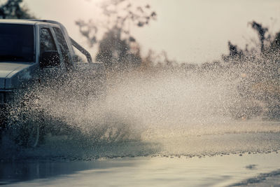 Water splashing on car against sky