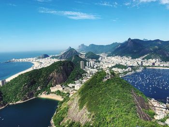 High angle view of sea and mountains against blue sky