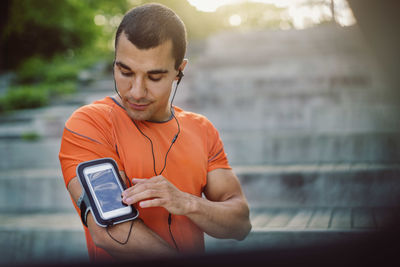 Man using smart phone armband while standing at steps