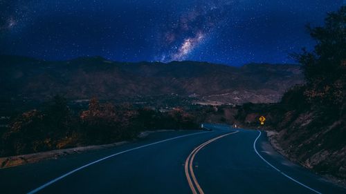 Road amidst mountains against sky at night