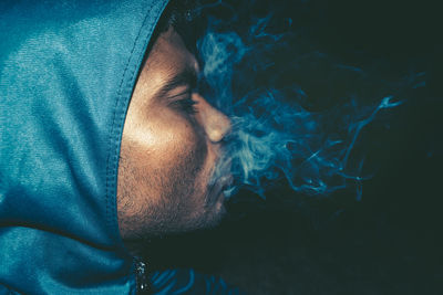 Close-up of man smoking against black background