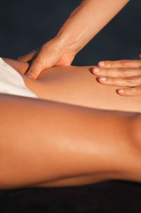 Cropped hands of masseuse giving massage on leg of woman