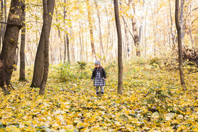 Rear view of woman walking in forest during autumn