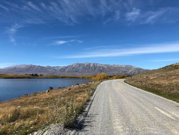 Scenic view of road by mountains against sky