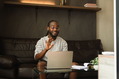 Young woman using laptop while sitting on sofa at home