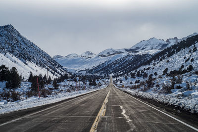 Road amidst snowcapped mountains against sky