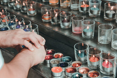 Cropped hands by lit tea light candles on steps