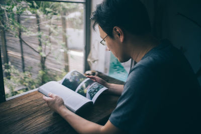 Side view of man reading book at home