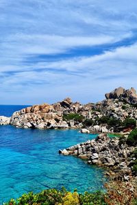 Rock formation by sea against blue sky