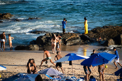 People are seen during strong sun on praia da barra in the city of salvador, bahia.