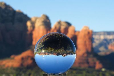 Close-up of crystal ball on rock against sky