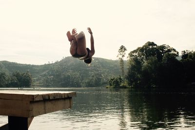 Woman diving in lake against clear sky