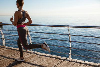 Full length of woman running by railing against sea