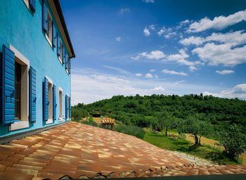 Footpath by buildings against blue sky