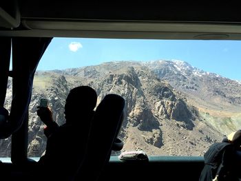 Rear view of man and woman against sky seen through window