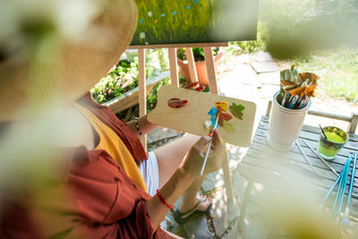 Young female artist working on her art canvas painting outdoors in garden. creative hobby concept.