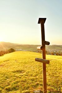 Close-up of cross on field against sky