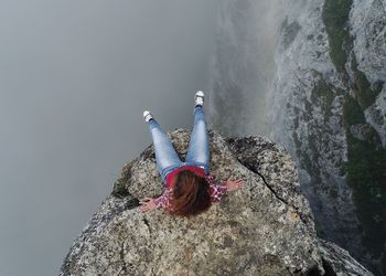 Directly above shot of woman sitting on cliff by lake