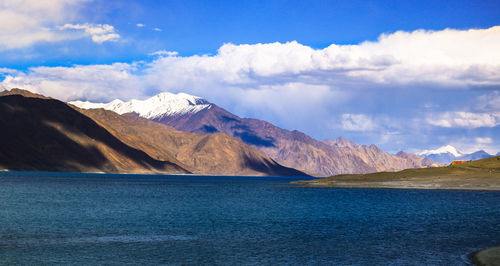 Scenic view of lake by mountains against sky