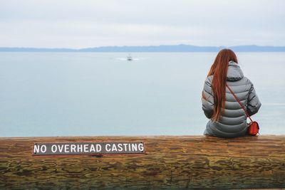 Woman by sea against sky