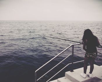 Rear view of woman standing by sea