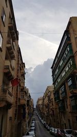 Vehicles on road amidst buildings against sky