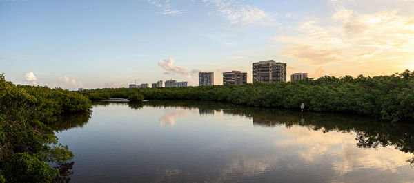 View of lake by buildings against sky during sunset