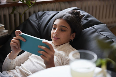 Girl lying on bean bag and playing video games