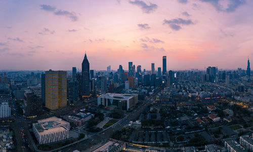 Aerial view of modern buildings in city against sky during sunset