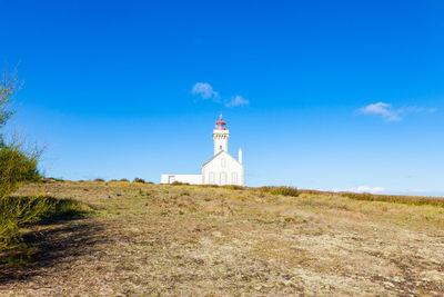 Lighthouse on field against sky