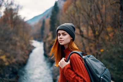 Portrait of beautiful young woman standing against trees during winter